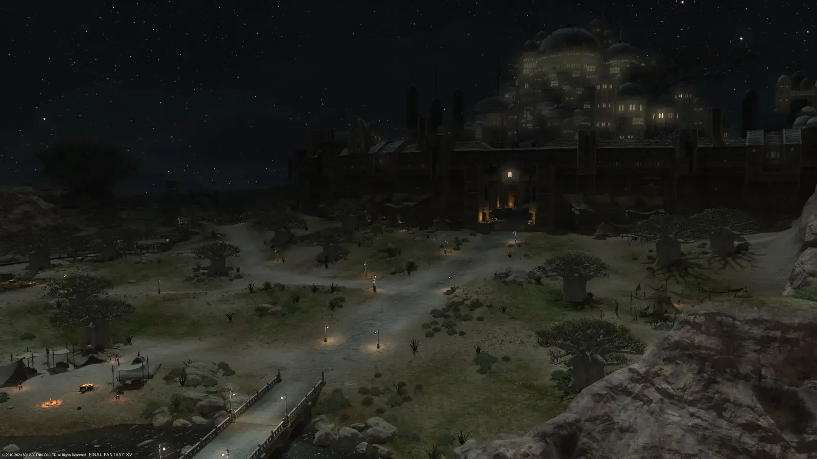 A nighttime view of Ul'dah can be seen from above the plains. A campsite and rail station can be seen to the left.